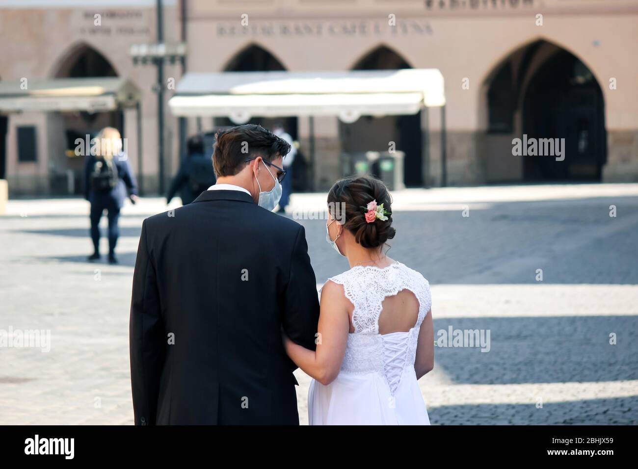 Prague, République tchèque - 23 avril 2020: Couple de mariage dans les masques médicaux de visage dans la vieille ville. Mariage pendant la pandémie de coronavirus. Mariages COVID-19. Photo horizontale. Banque D'Images