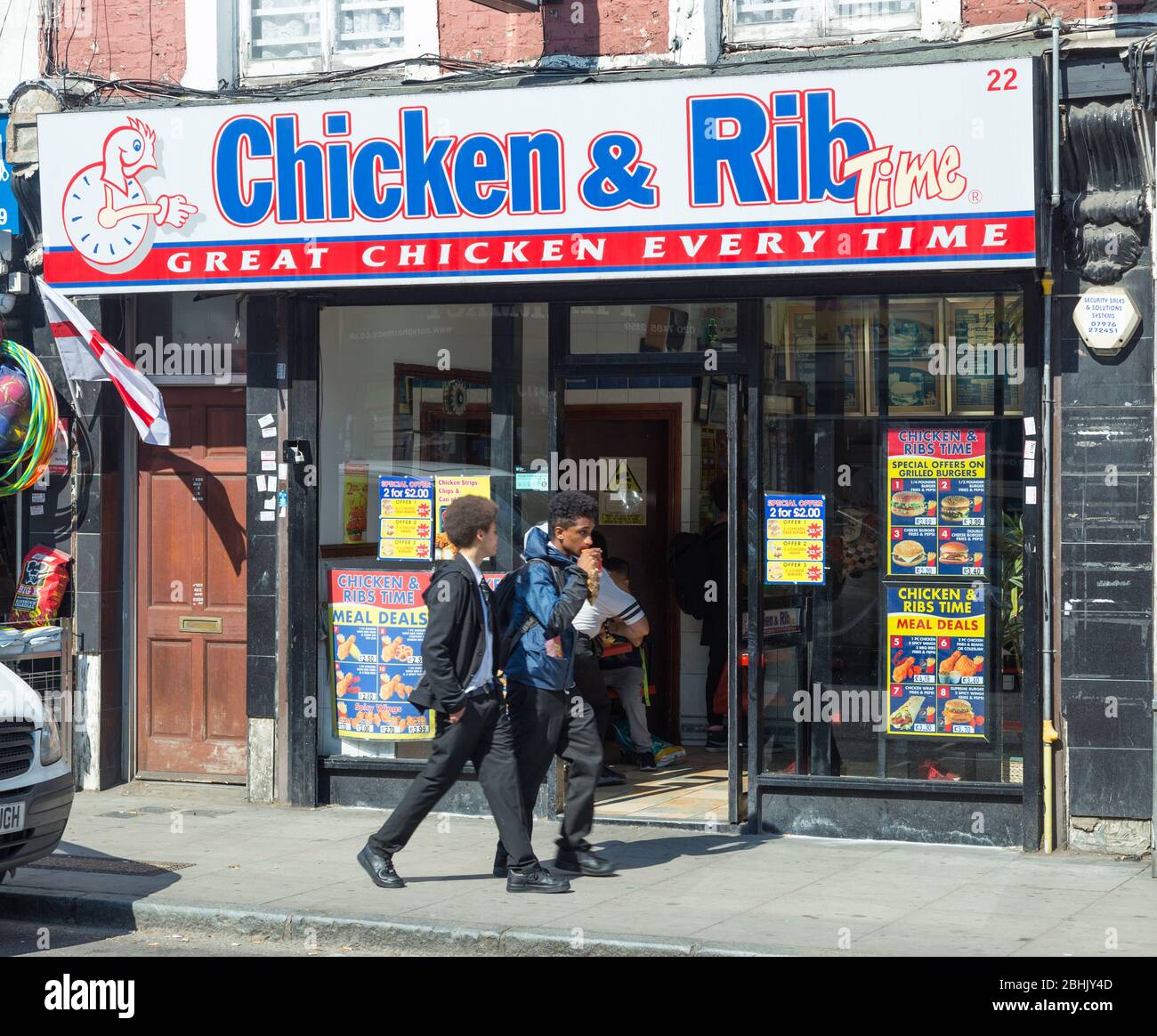 Deux écoliers marchent devant un magasin de poulet à emporter à Kentish Town, dans le nord de Londres Banque D'Images