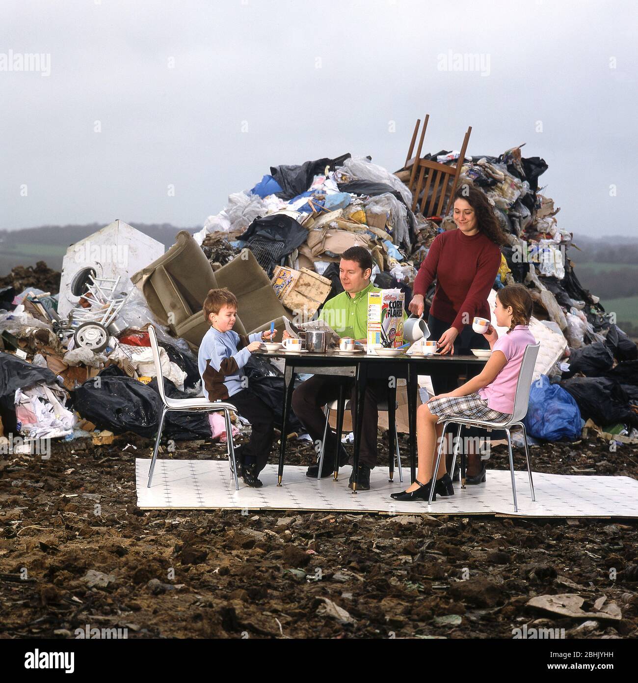 Famille devant un tas de déchets de remplissage de terre produits par la famille moyenne Banque D'Images