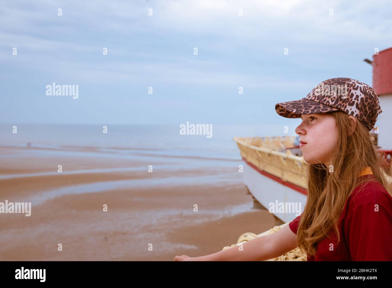 Une adolescente sur la jetée centrale de Blackpool en regardant de manière réfléchie sur la plage et la mer. Avec espace blanc Banque D'Images