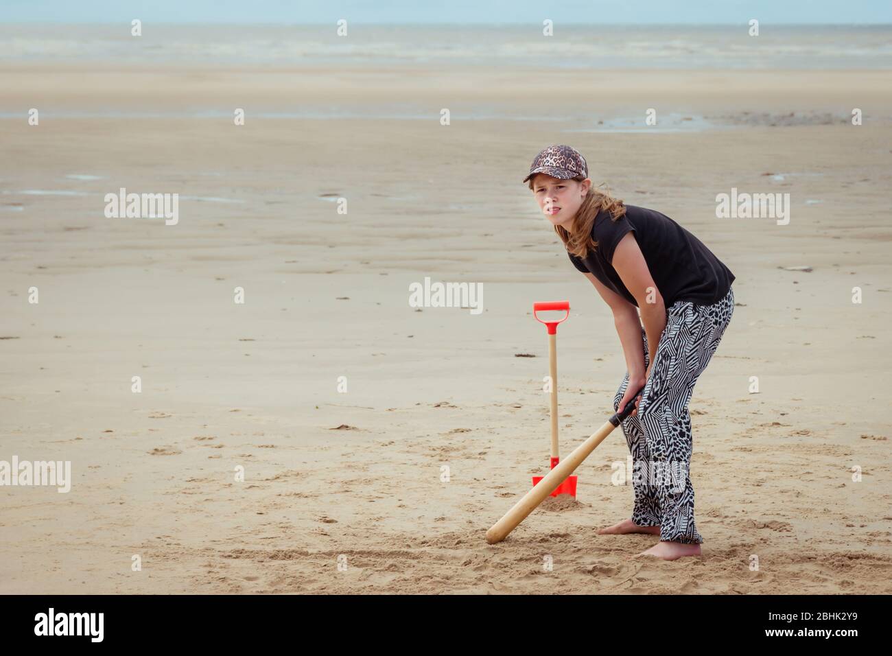 Une adolescente en vacances en bord de mer familiale jouant au cricket avec une batte de baseball sur la plage Banque D'Images