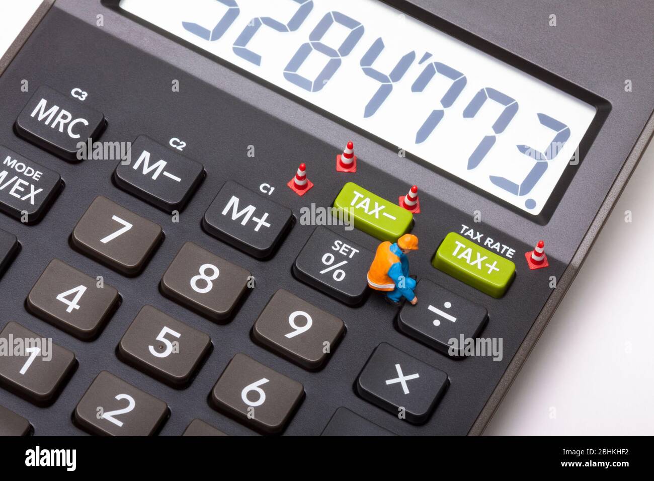 Image conceptuelle d'un homme de travail à figure miniature à côté des boutons marqués TAX Banque D'Images