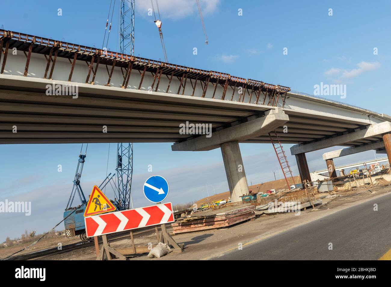 Nouveau pont routier moderne pont de passage supérieur site de contraste avec vue au-dessus de la chaussée avec des machines industrielles lourdes et ciel bleu sur fond. Ville urbaine Banque D'Images