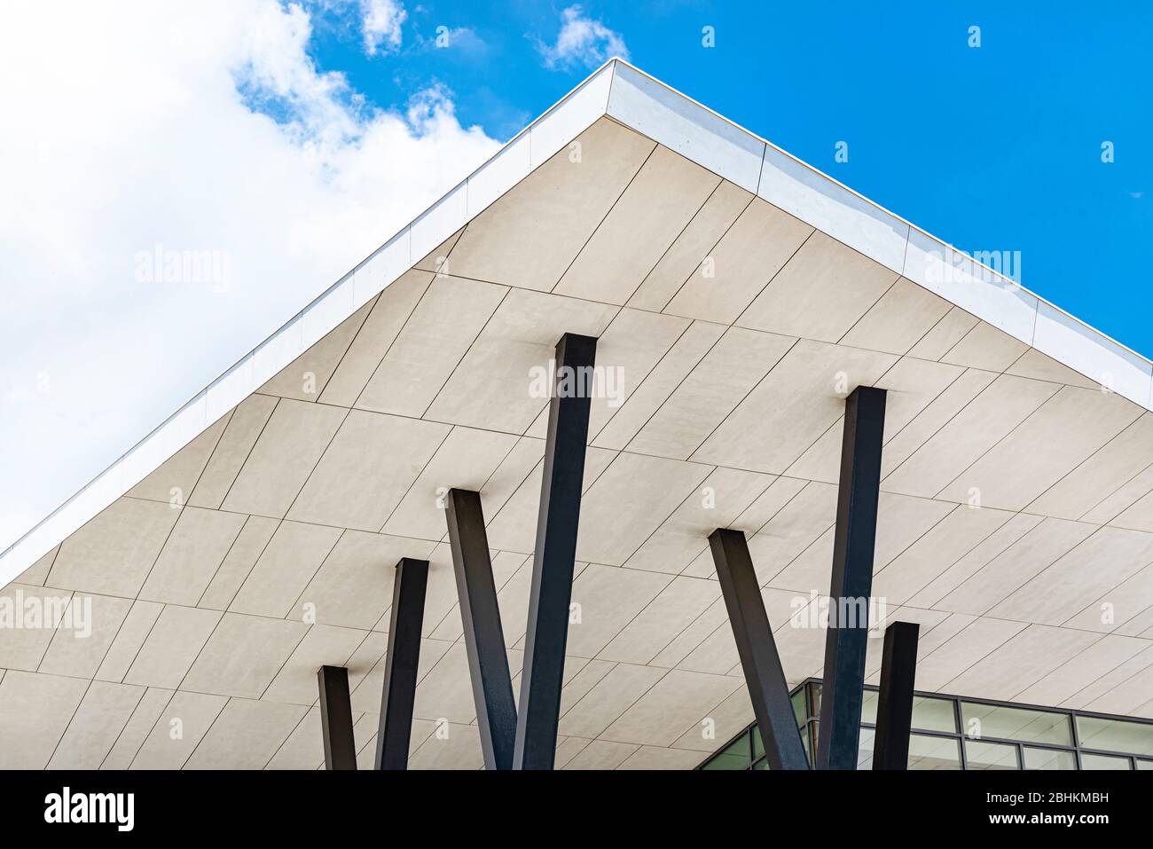 Un toit en béton moderne soutenu par des piliers en acier contre un ciel bleu avec des nuages. Banque D'Images