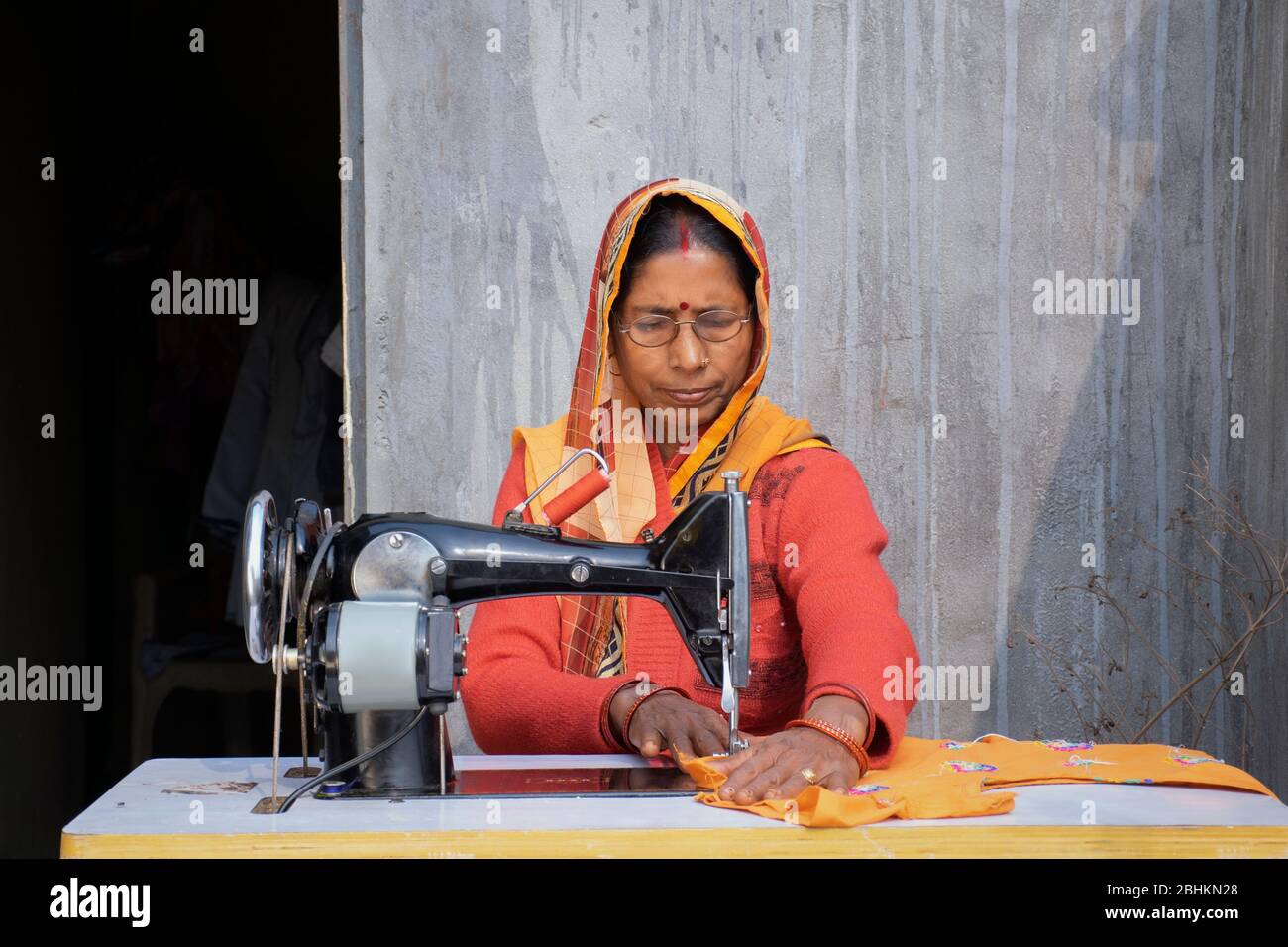 femme sur machine à coudre à fabriquer des vêtements dans un village rural indien Banque D'Images