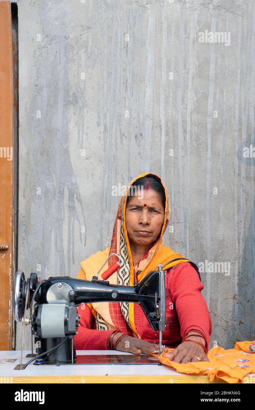femme sur machine à coudre à fabriquer des vêtements dans un village rural indien Banque D'Images
