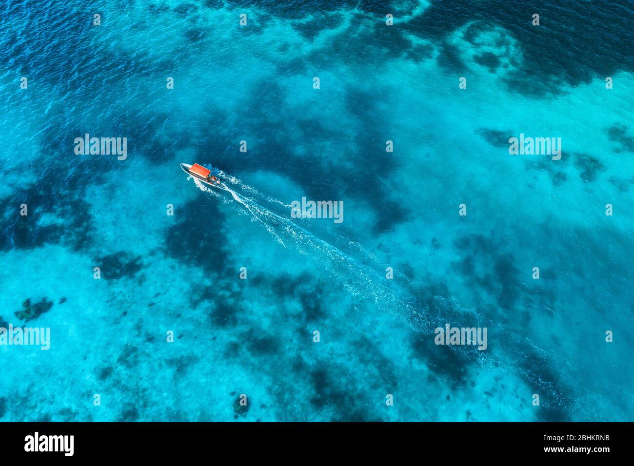 Vue aérienne du bateau blanc dans l'eau bleu clair au coucher du soleil Banque D'Images