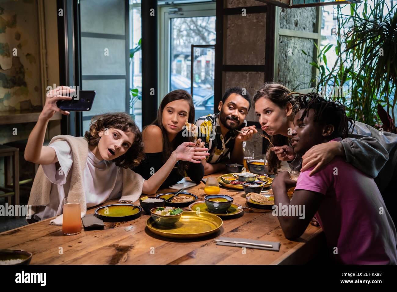 Cinq jeunes amis assis à la table dans un café, prendre ...