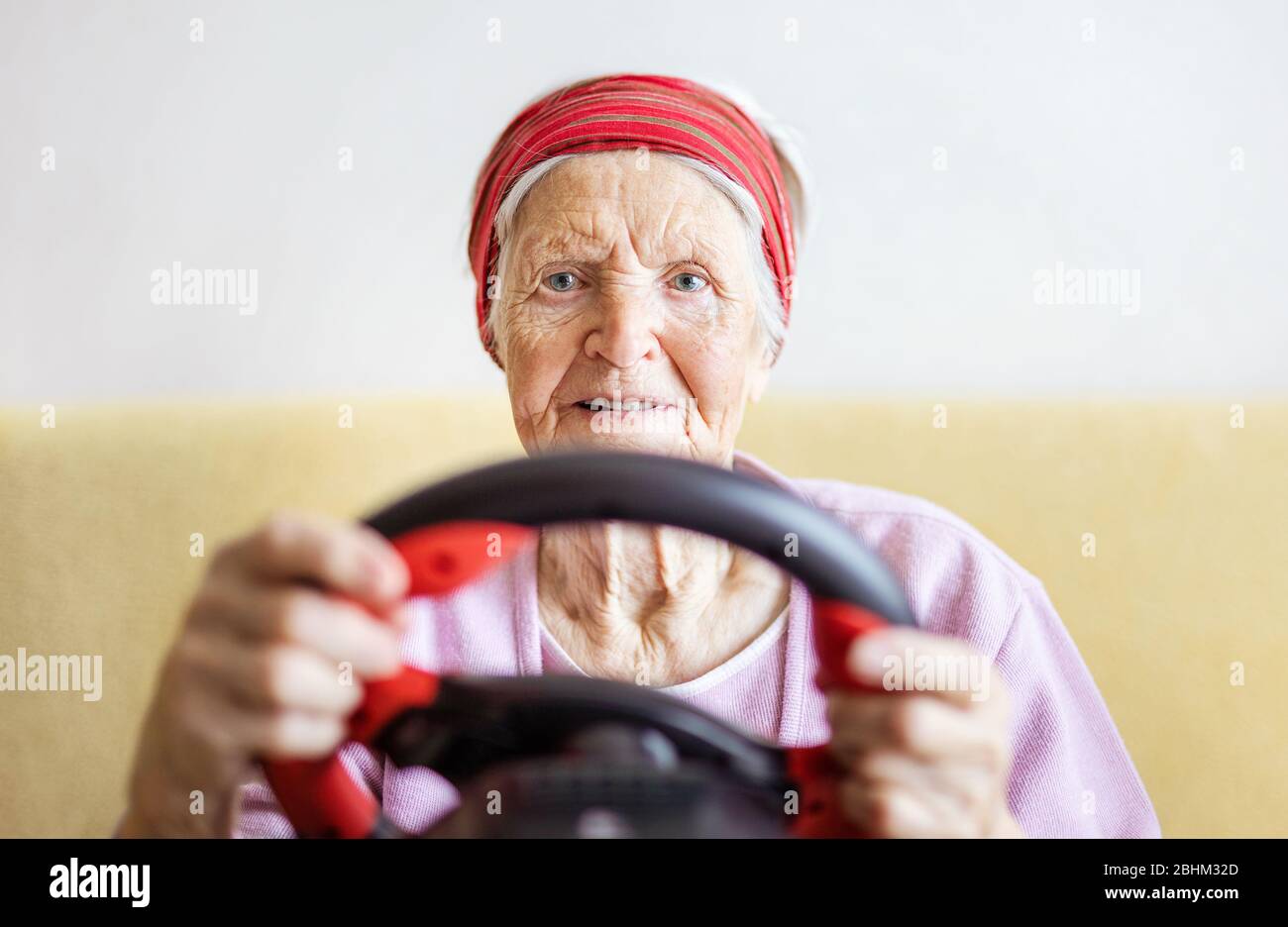 Femme senior qui aime jouer à la voiture de course vidéo à la maison Banque D'Images
