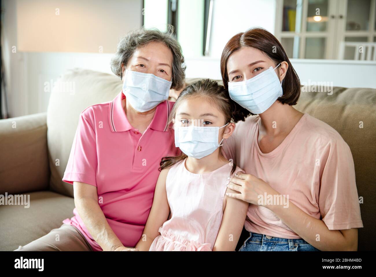 La mère et la grand-mère aident la fille à porter un masque facial pour prévenir la pollution atmosphérique et le coronavirus COVID-19 Banque D'Images