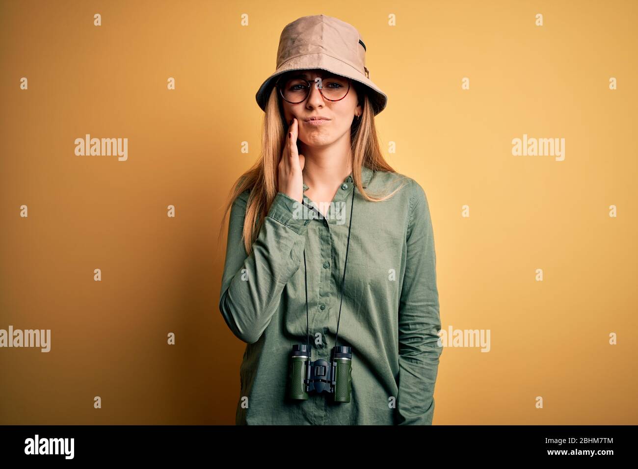 Belle Femme Blonde Explorer Avec Yeux Bleus Portant Chapeau Et Lunettes À  L'aide De Jumelles Touchant La Bouche Avec La Main Avec L'expression  Douloureuse À Cause De À Photo Stock - Alamy