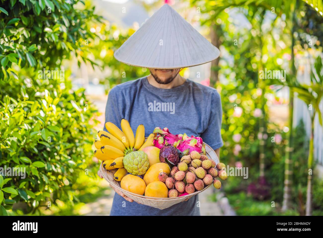 Variété de fruits dans un chapeau vietnamien. Homme dans un chapeau  vietnamien Photo Stock - Alamy