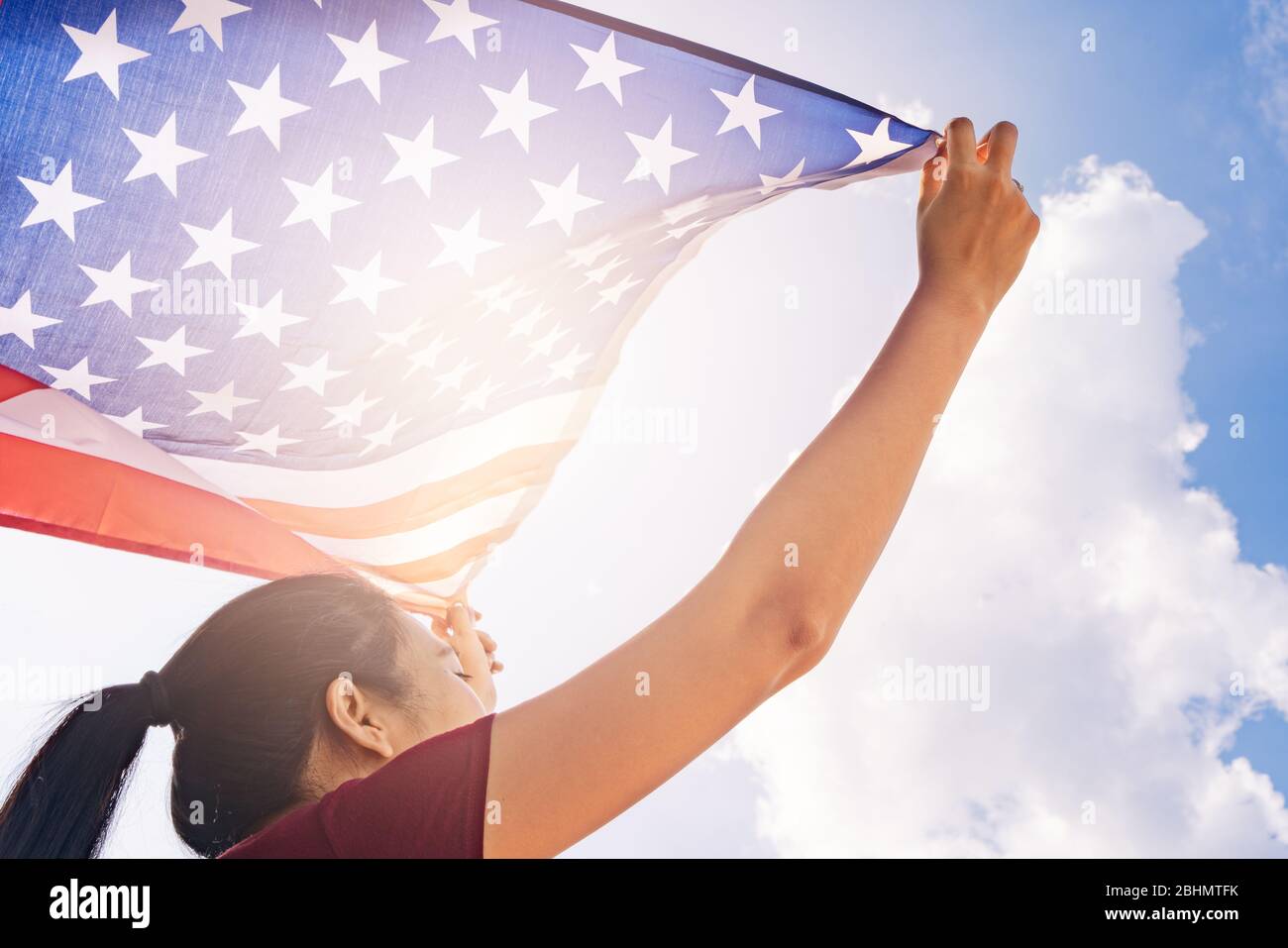Femme tenant le drapeau des États-Unis d'Amérique sur le ciel ensoleillé. USA Memorial Day et Independence Day concept. Banque D'Images