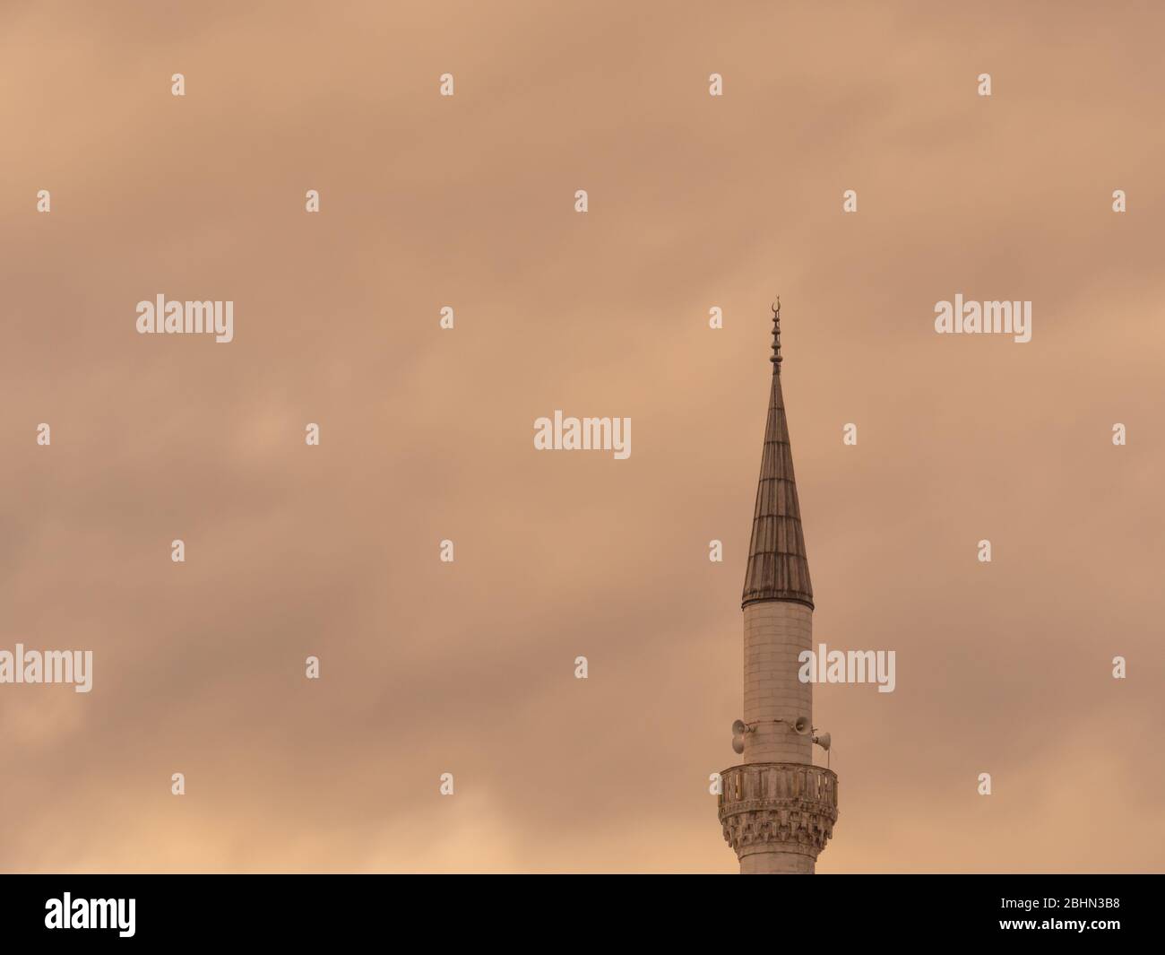 Minaret d'une mosquée musulmane sur le fond du ciel nuageux. Minaret aspirant au ciel. Banque D'Images