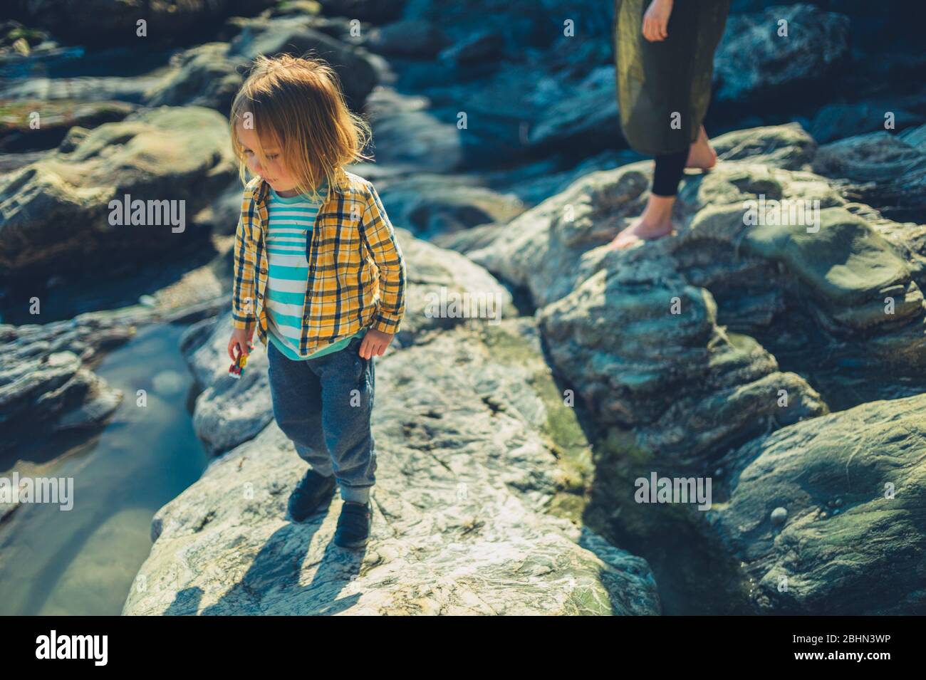 Une jeune mère et son enfant d'âge préscolaire marchent sur les rochers et les falaises au bord de la mer Banque D'Images
