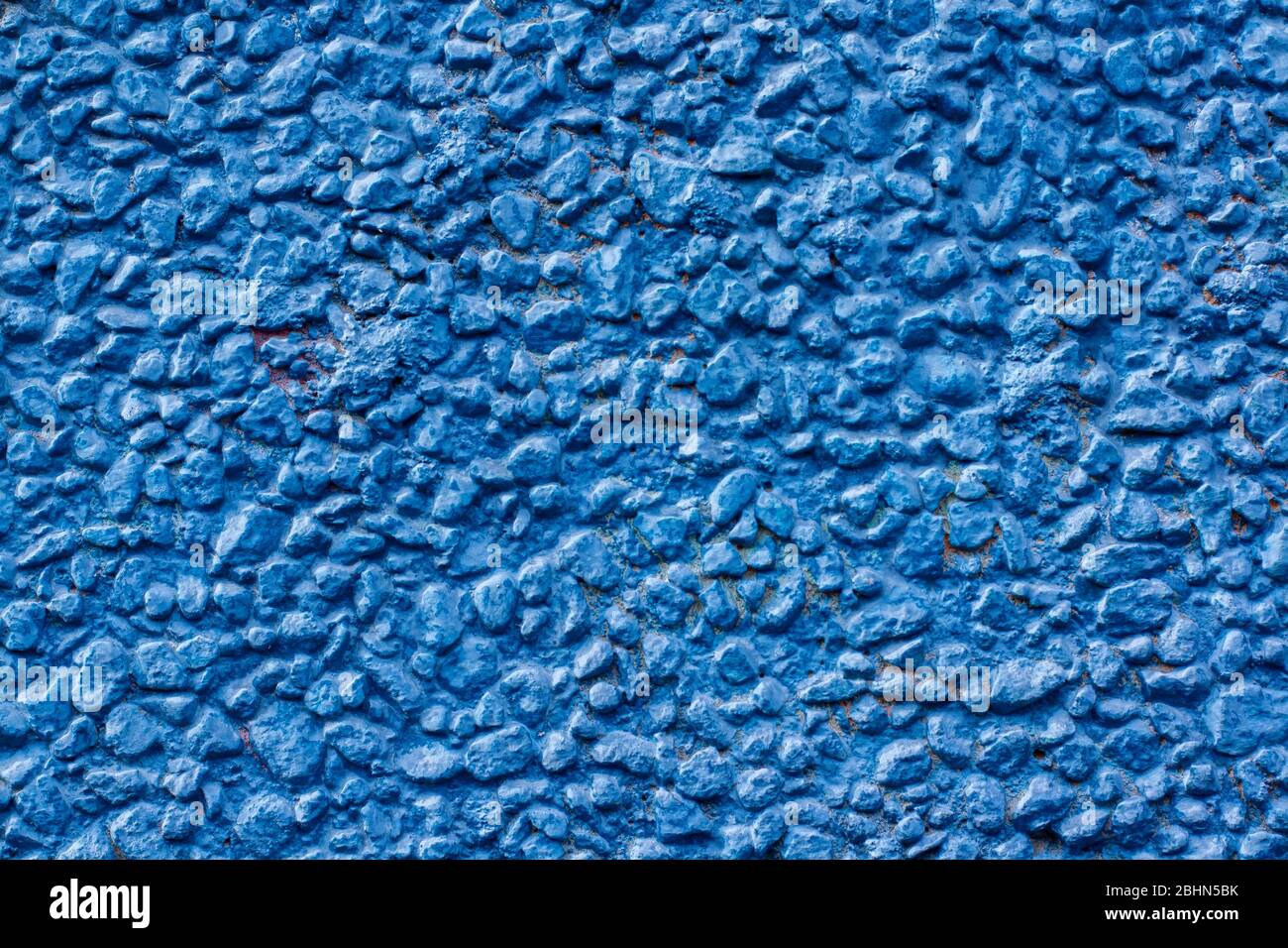 Texture de fond de petites cailloux peints avec de la peinture bleue. Pierres attachées avec une solution sur un mur à la maison. Horizontal. Banque D'Images
