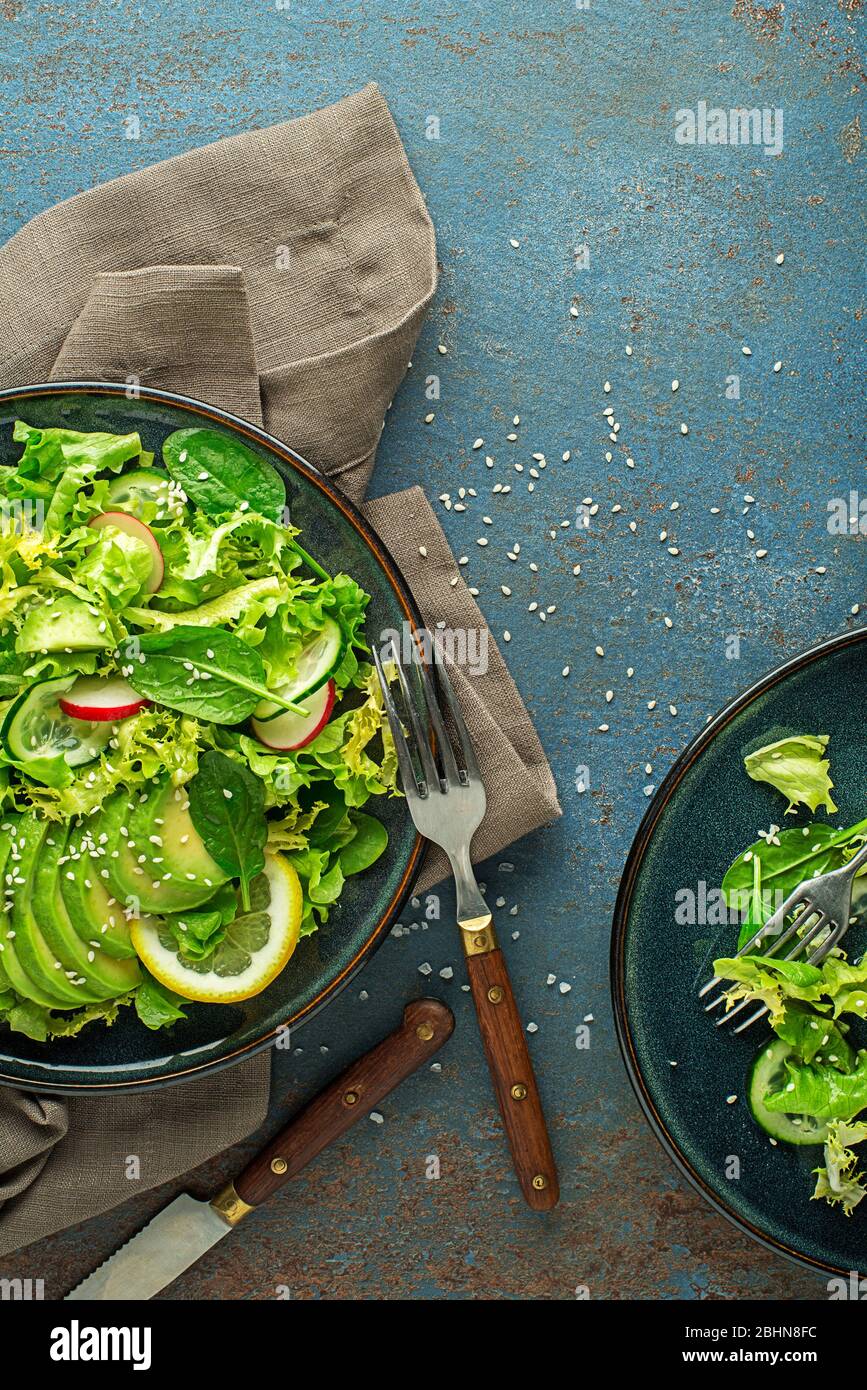Manger une salade verte saine avec avocat et radis sur la table bleue Banque D'Images