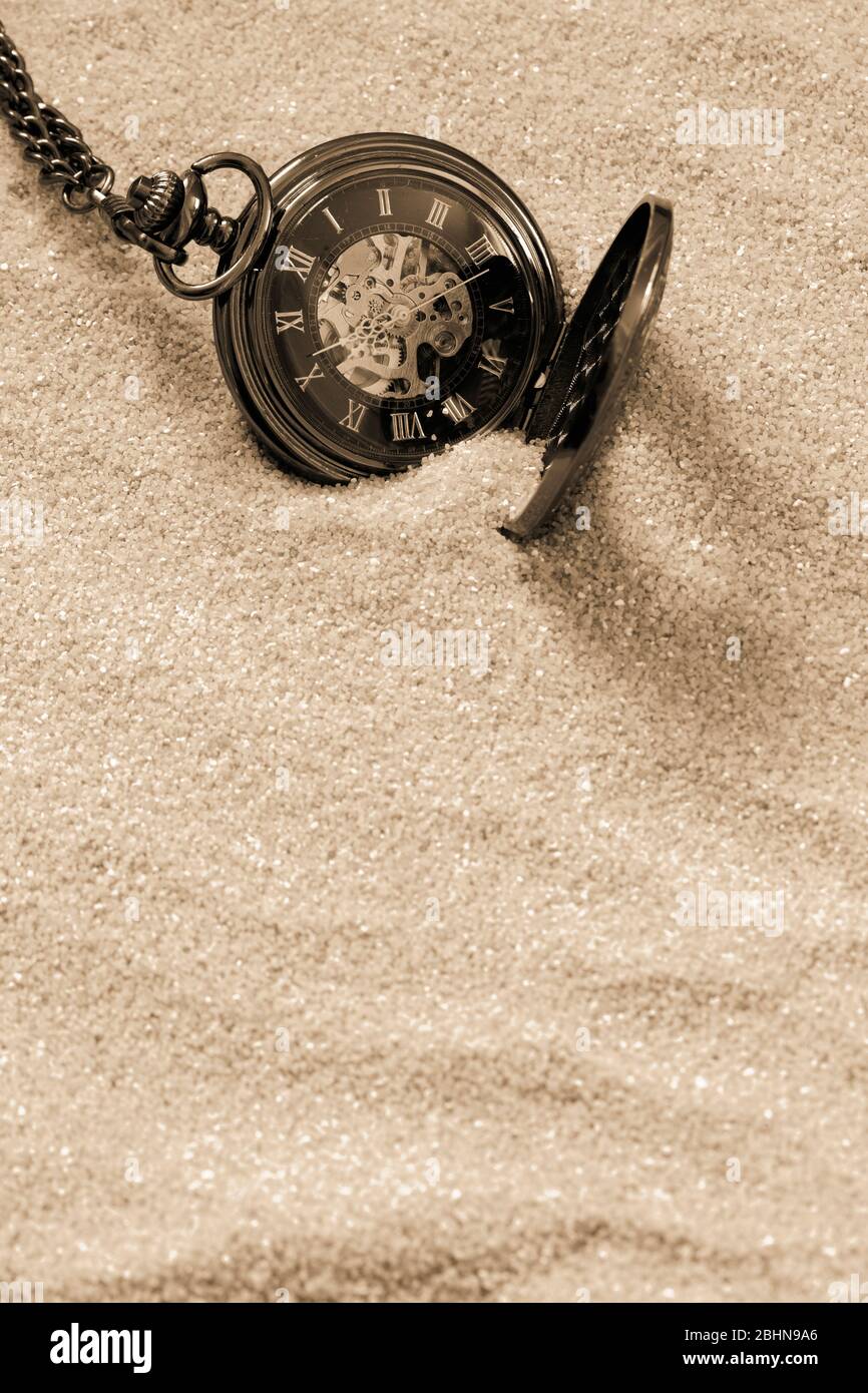 Montre ancienne de poche avec chaîne en partie enfouie dans le sable. Avec ton couleur Banque D'Images