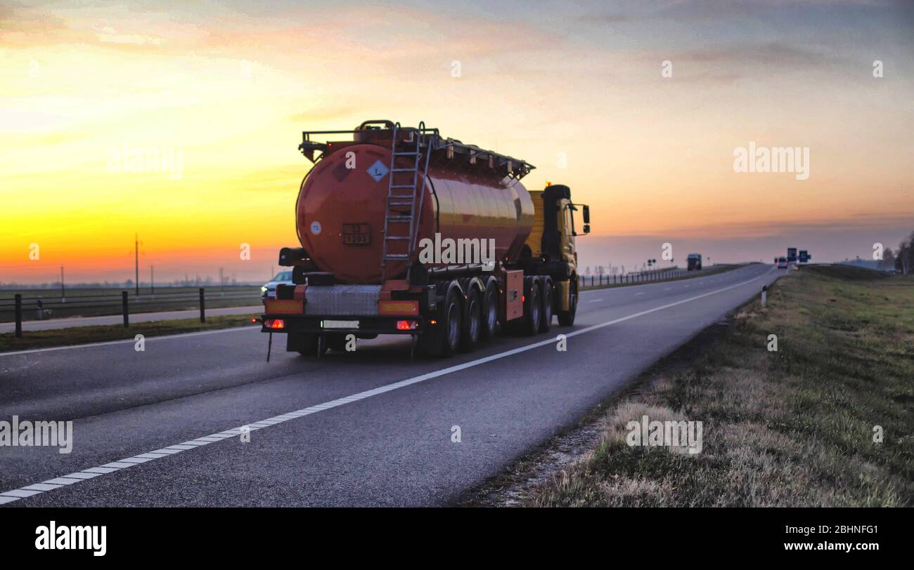 Un camion transporte un réservoir de combustible sur une autoroute contre une forêt et un ciel bleu. Le concept de transport de marchandises dangereuses sur la route, l Banque D'Images