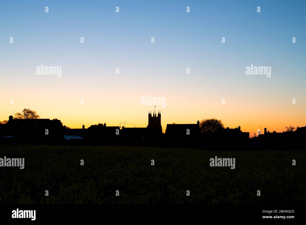Tour de l'église St Pierre et St Paul et maisons à l'aube à Deddington, Oxfordshire, Angleterre. Silhouette Banque D'Images