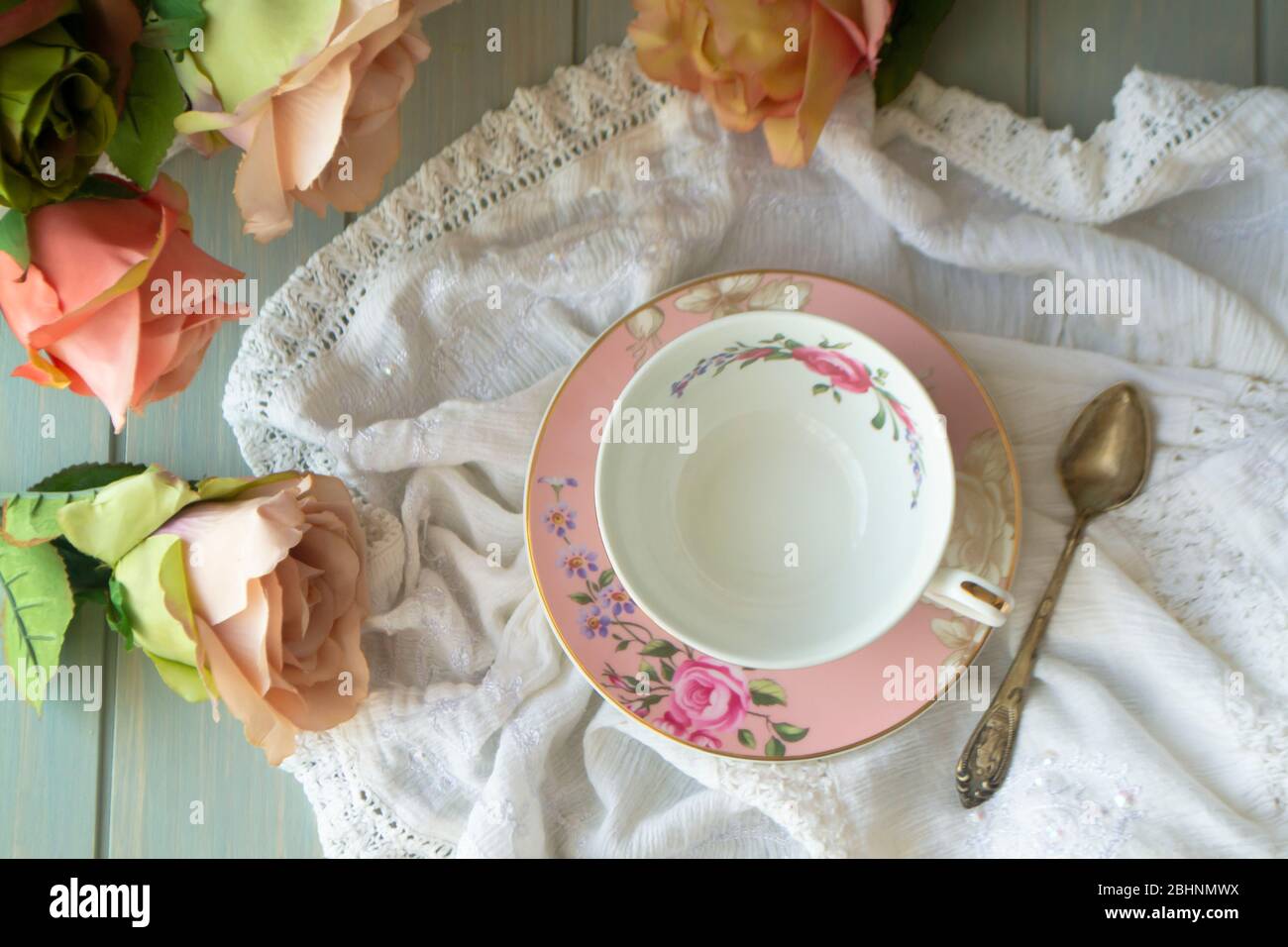 Tasse à thé vintage avec bordure en or. Nappe en lin blanc. Roses pastel, plat Banque D'Images