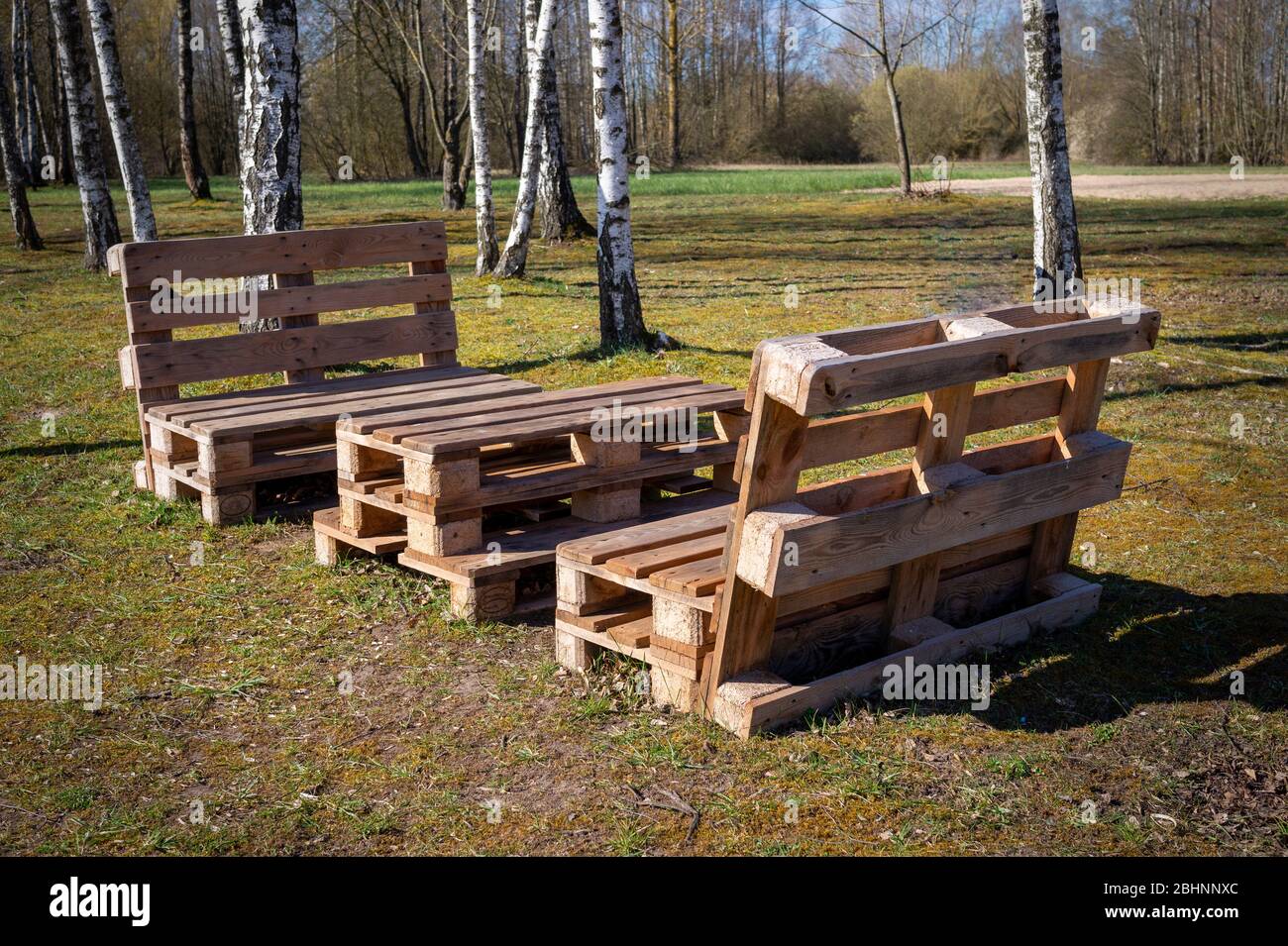 Table et bancs en bois rustique faite avec des palettes sur la rive d'un lac d'un calme entouré d'arbres et de verdure dans le soleil d'été Banque D'Images