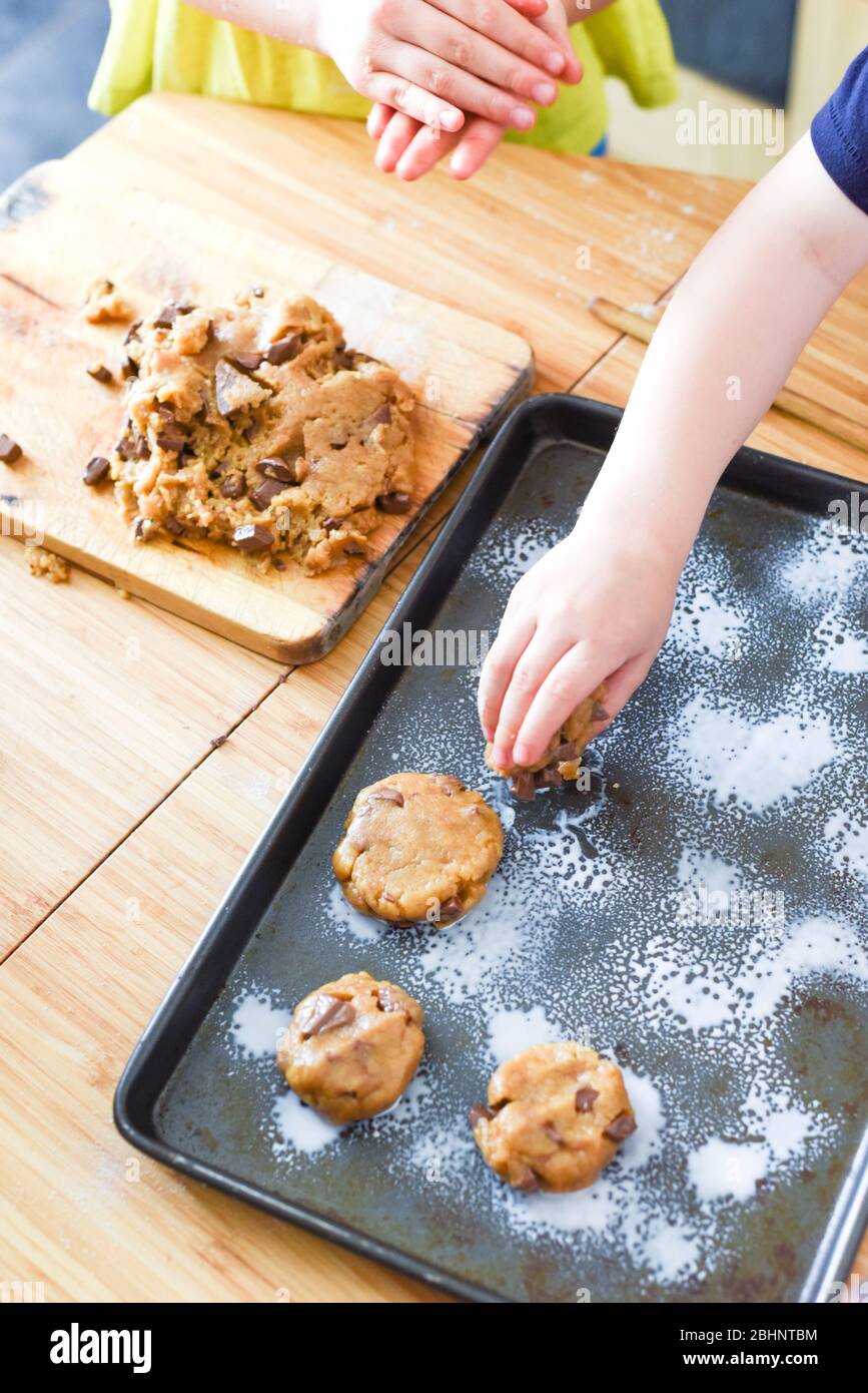 Les enfants font des biscuits dans la cuisine en plaçant la pâte sur le plateau pour la cuisine à la maison Banque D'Images