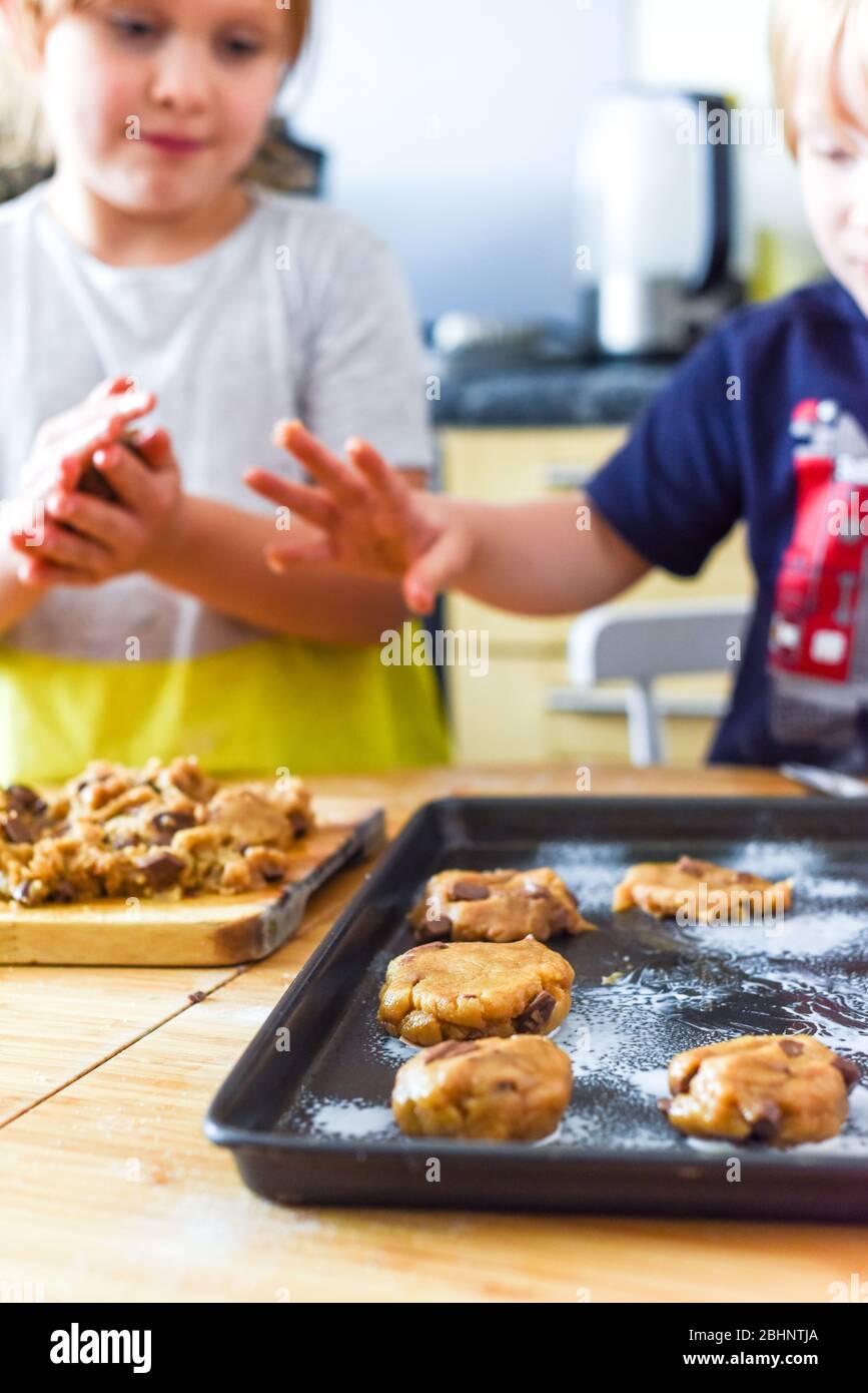 Les enfants font des biscuits dans la cuisine en plaçant la pâte sur le plateau pour la cuisine à la maison Banque D'Images