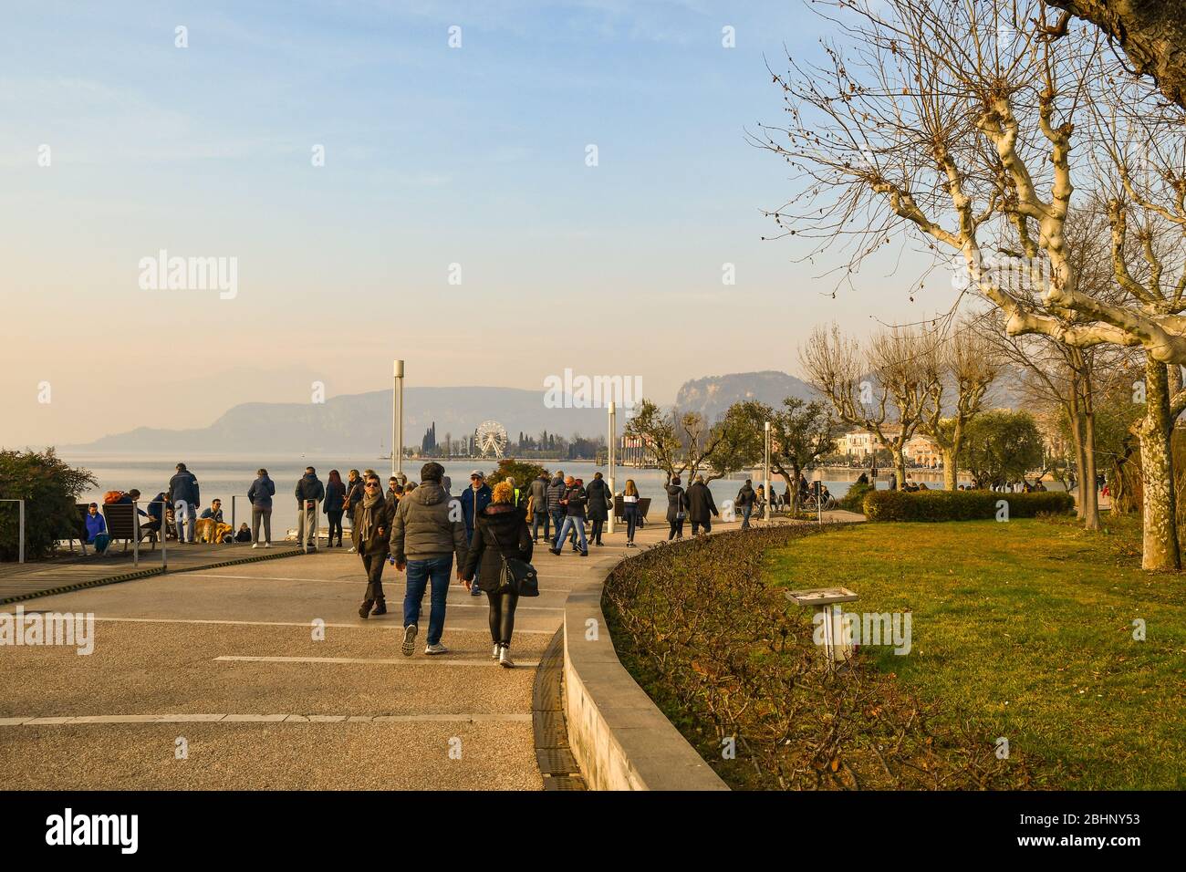 Les gens et les touristes marchant sur la promenade au bord du lac de la vieille ville de Bardolino sur le rivage du lac de Garde en hiver au coucher du soleil, Vérone, Italie Banque D'Images