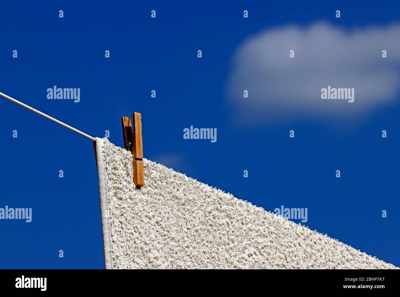 Séchage d'un tapis sur une ligne de lavage avec une seule broche sur une diagonale de composition avec un ciel bleu et un fond de nuage blanc. Banque D'Images