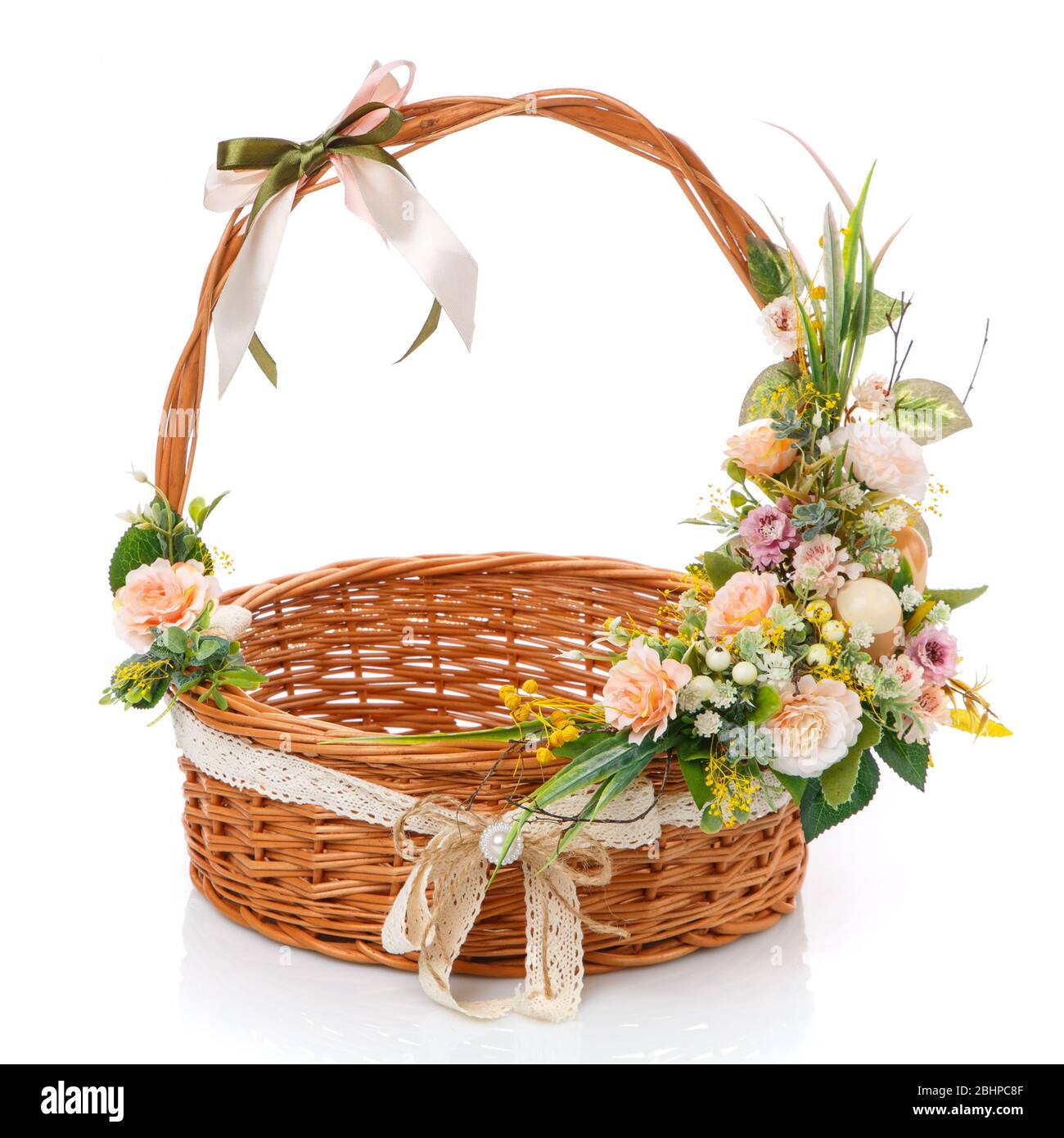 Le panier rond de vigne naturel est décoré avec des fleurs délicates, des œufs de Pâques et du filet sur fond blanc Banque D'Images