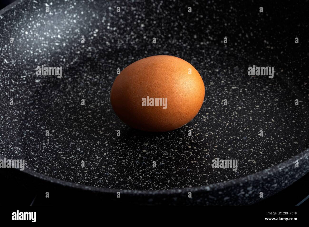 Un œuf biologique non cuit dans une poêle noire Banque D'Images