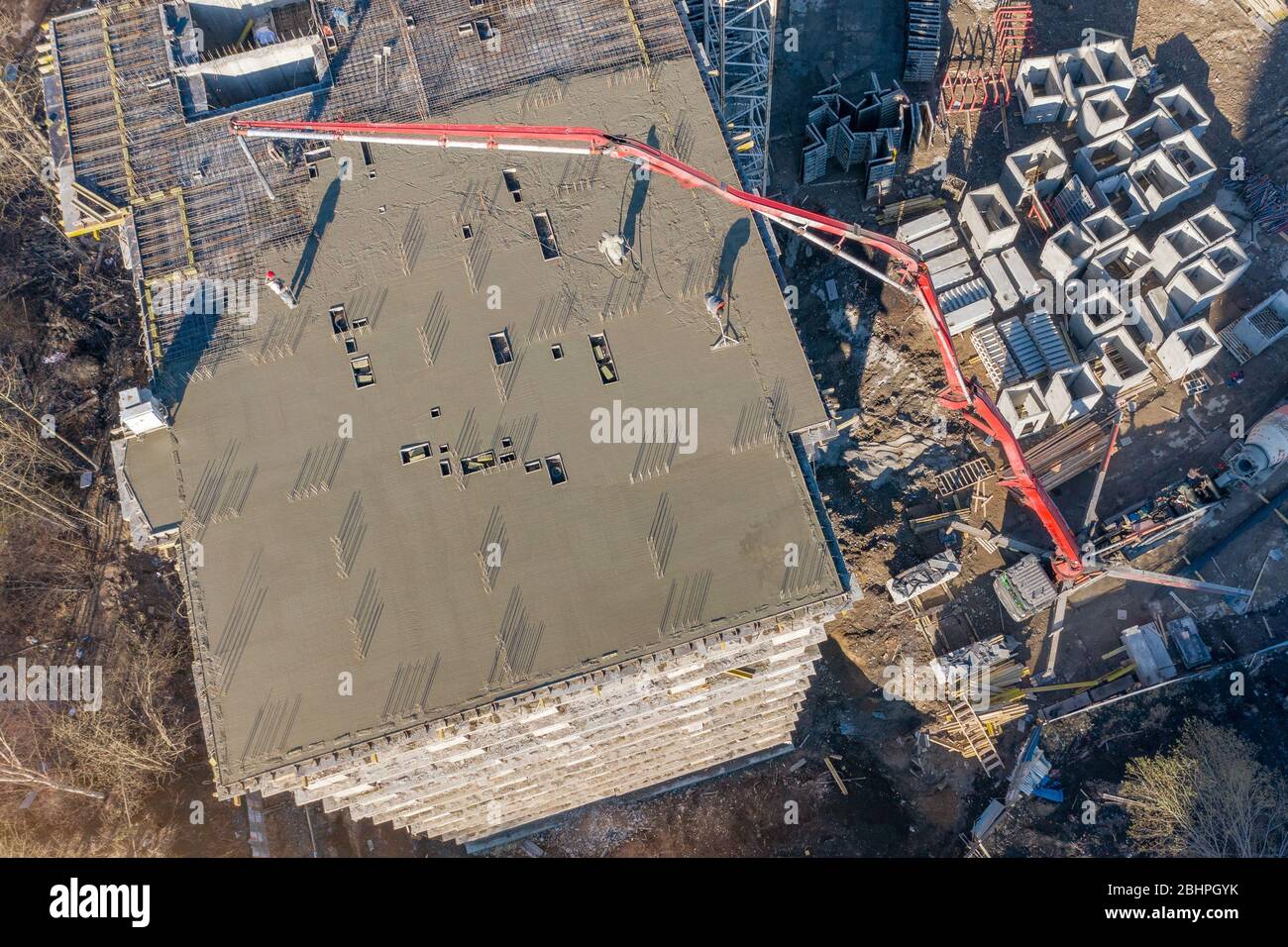 Verser du ciment sur les sols d'un bâtiment résidentiel à plusieurs étages en construction à l'aide d'un camion à pompe en béton à forte flèche pour alimenter le mélange t Banque D'Images