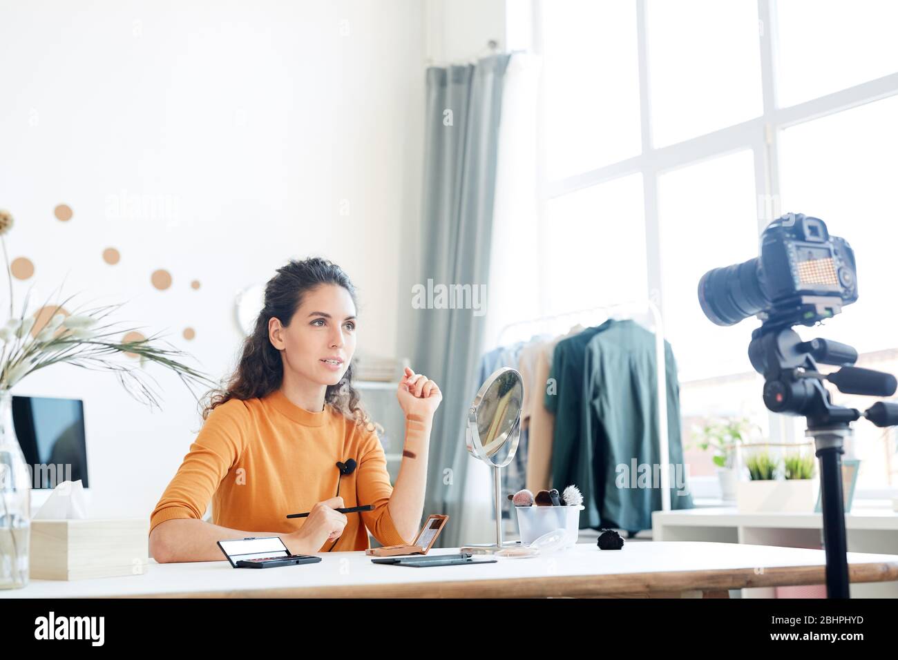 Blogueur de beauté assis seul dans sa chambre expliquant quelque chose aux spectateurs, prise horizontale Banque D'Images