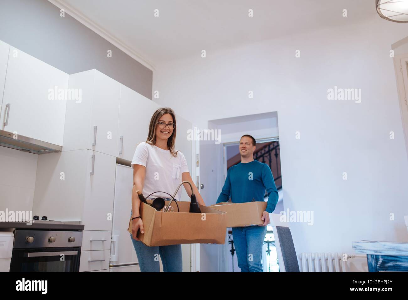 Un homme et une femme caucasiens attirants entrent dans un nouvel appartement avec des boîtes de choses. Un couple affectueux entre en action Banque D'Images