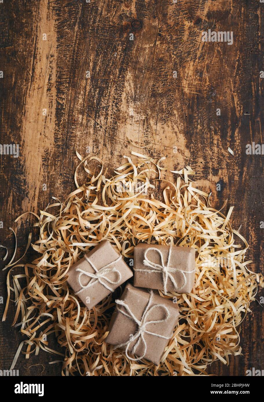 Petites boîtes-cadeaux rustiques sur fond texturé en bois avec espace pour le texte. Vue de dessus Banque D'Images