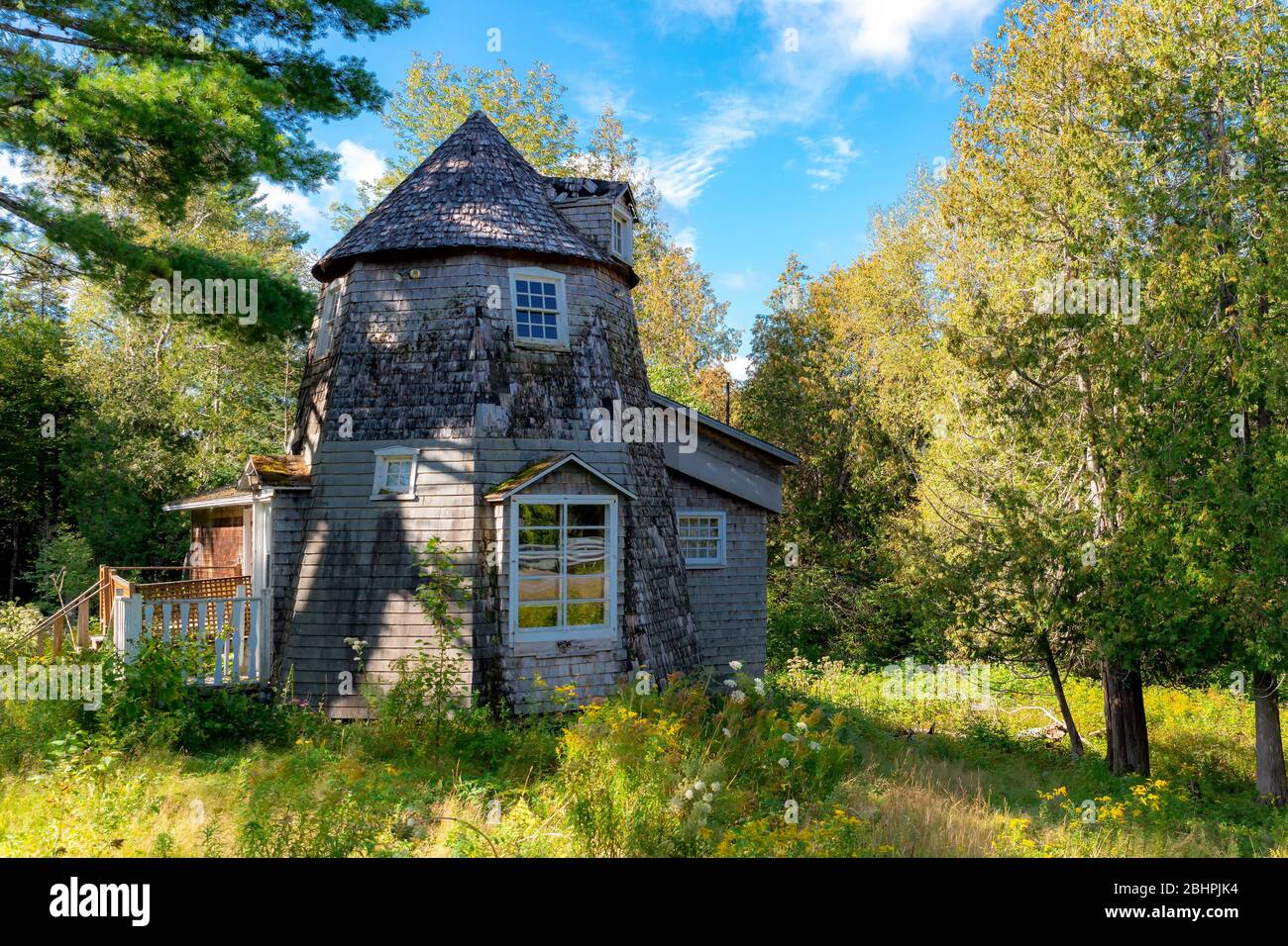Une maison abandonnée dans un champ dans les bois. La maison a une tour qui est décorée après un moulin à vent néerlandais. Les bardeaux en bois sont en rotants, et en partie Banque D'Images