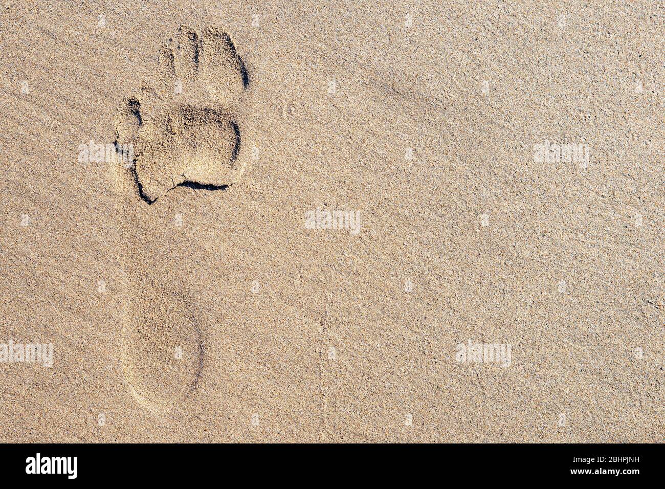 Une empreinte unique dans le sable sur une plage. Le pied était nu et le pied gauche. Beaucoup de place pour le texte. Banque D'Images
