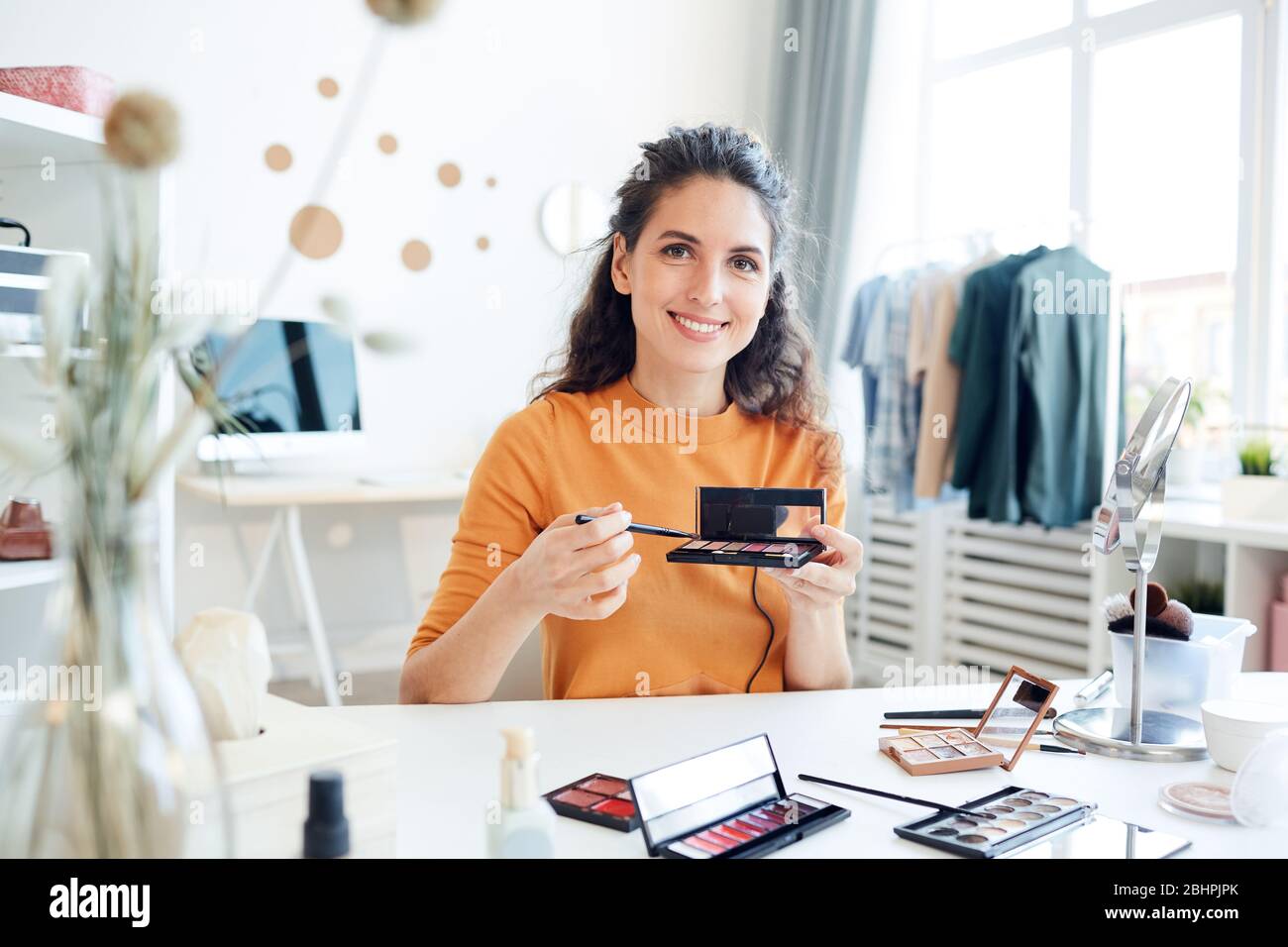 Portrait de beau blogueur de beauté tenant la palette de contourage de visage regardant l'appareil photo souriant Banque D'Images