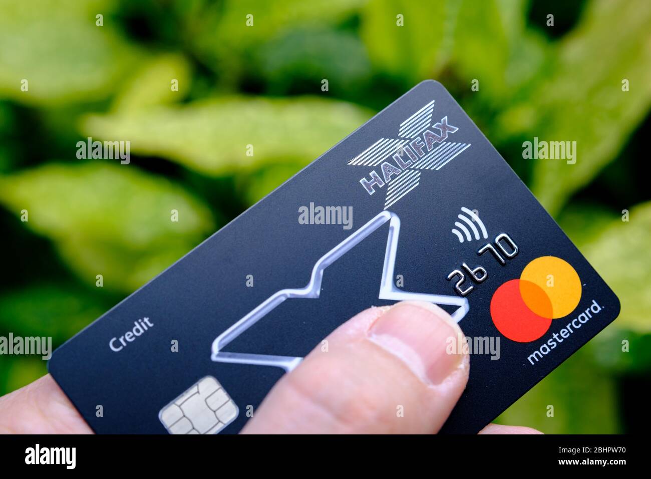 Stone / Royaume-Uni - 26 avril 2020: La carte de crédit Halifax Mastercard tient en main sur le fond vert. Banque D'Images