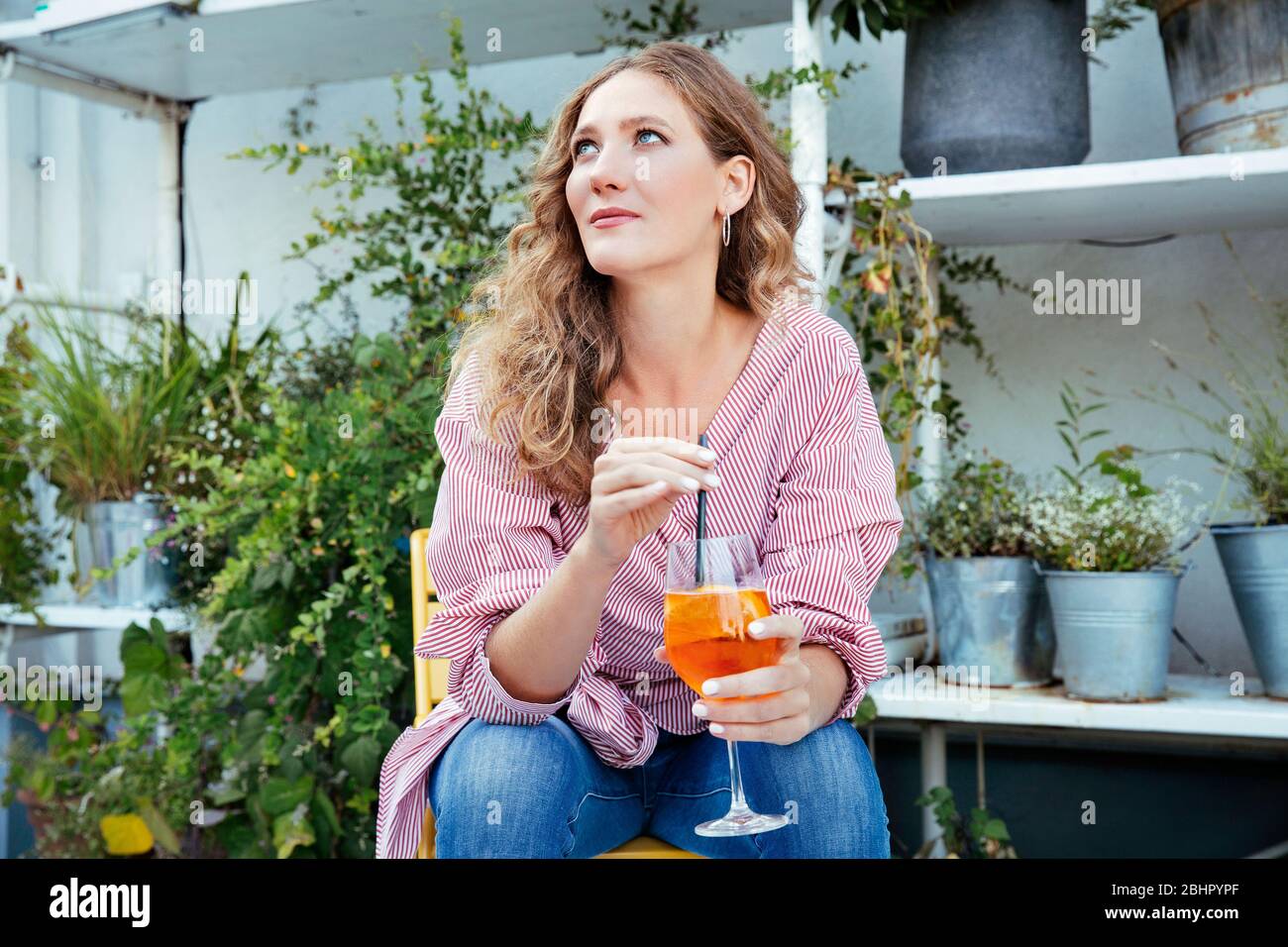 Une femme assise sur une terrasse qui a un verre Banque D'Images