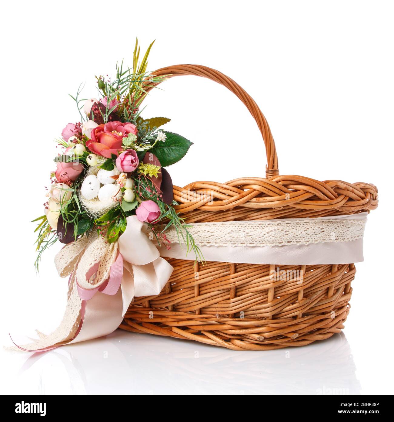 Panier en osier naturel avec fleurs et rubans. Magnifique noeud sur le côté. Isolé Banque D'Images