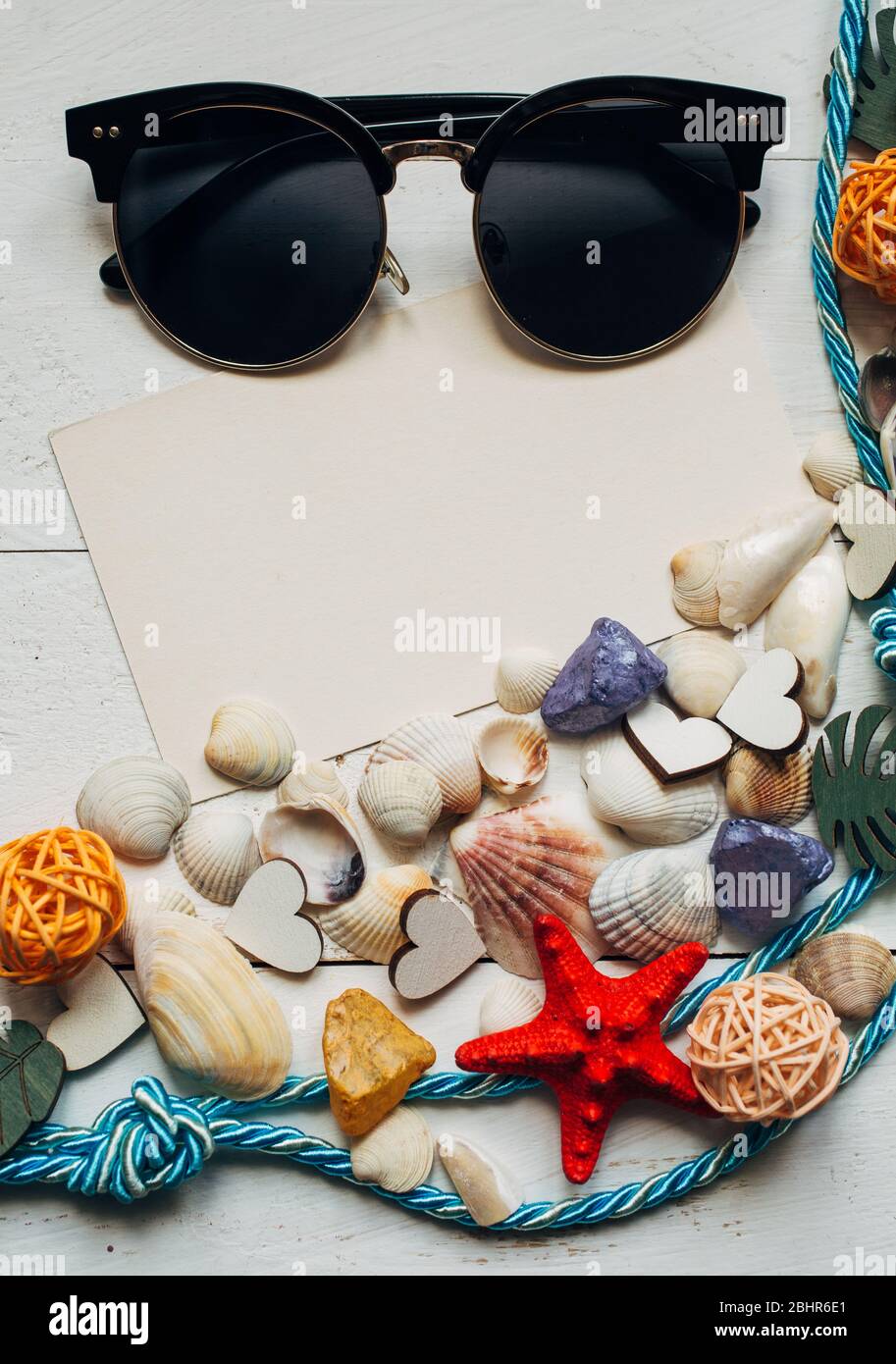 Différents types de coquillages, corde, lunettes de soleil et feuille  vierge avec place pour le texte sur fond en bois Photo Stock - Alamy