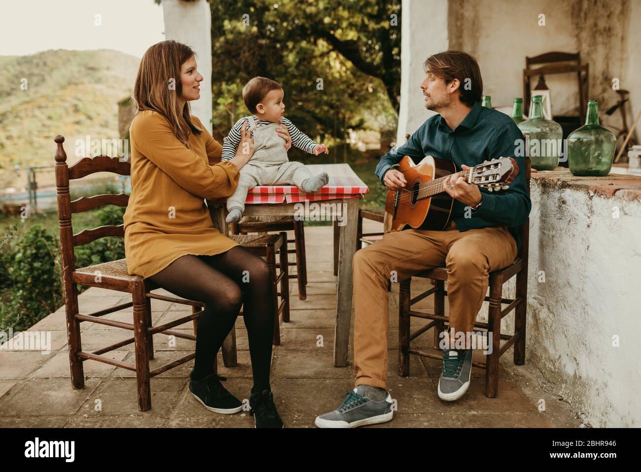 Beau Couple Avec Leur Bebe En Train De S Asseoir Sur La Cour A La Campagne L Homme Joue De La Guitare La Femme Tient Le Bebe Pendant Qu Il L Est Photo Stock Alamy Beau Couple Avec Leur Bebe En Train De S Asseoir Sur La Cour A La Campagne L Homme Joue De La Guitare La Femme Tient Le Bebe Pendant Qu Il L Est Photo Stock Alamy