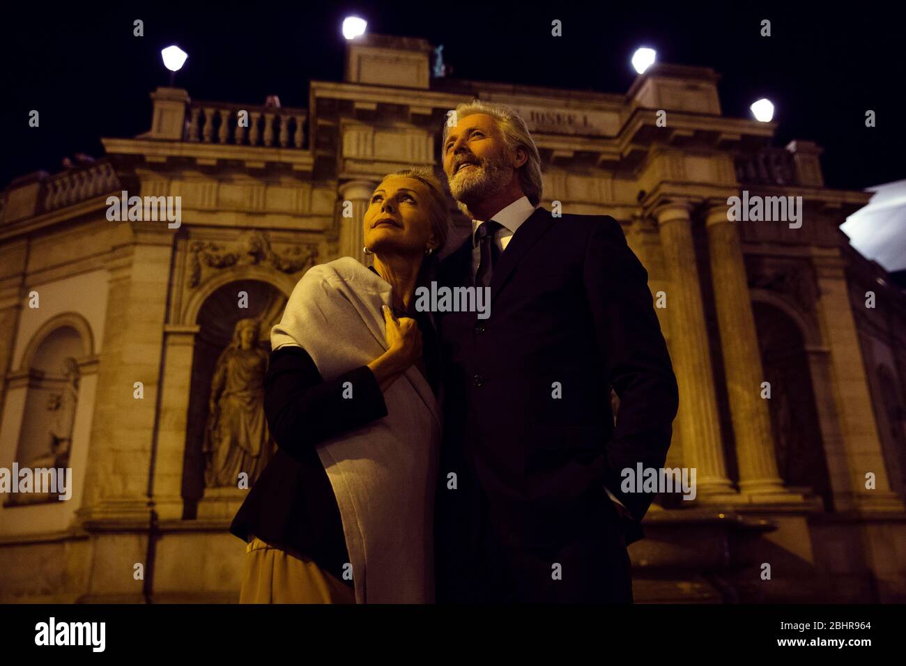 Un couple plus âgé se tenant debout les uns autour des autres et regardant dans une rue de Vienne le soir. Banque D'Images