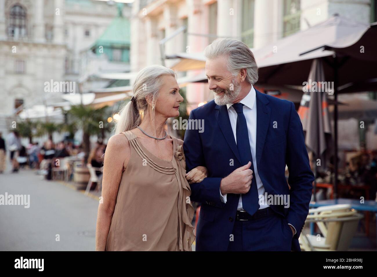 Un couple bras de marche dans le bras le long d'une rue avec des bars et des étals de marché à Vienne. Banque D'Images