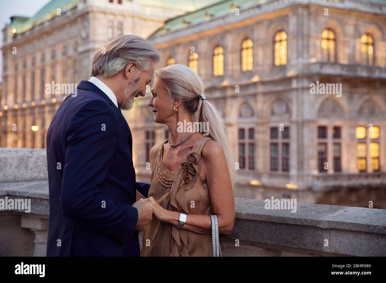 Un couple face à face et debout à proximité tenant les mains avec un bâtiment de Vienne en arrière-plan. Banque D'Images