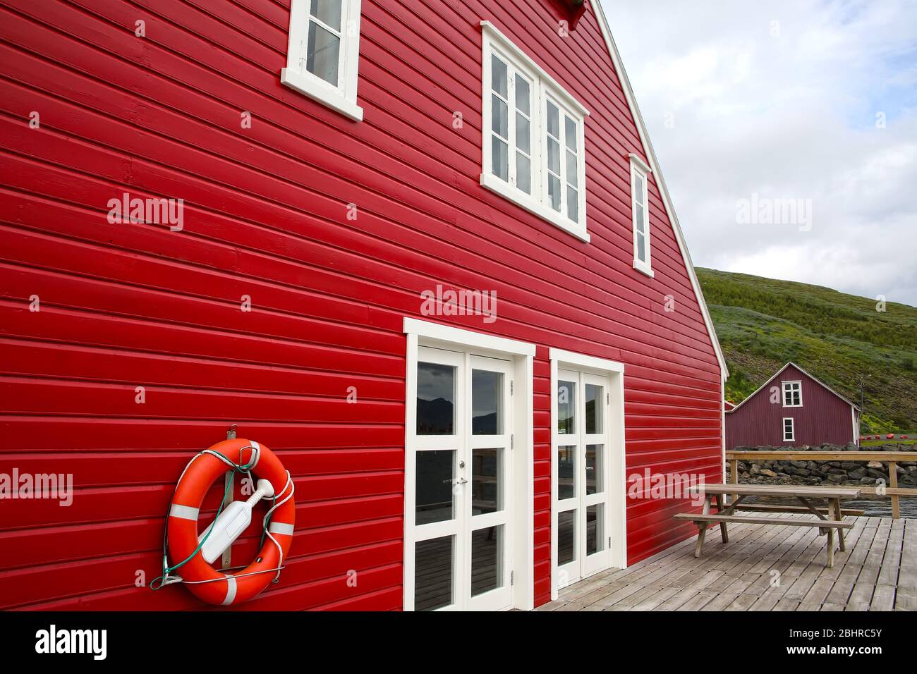 Maison traditionnelle en panneaux de bois peints en rouge avec terrasse en bois, Eskifjordur, est de l'Islande. Banque D'Images