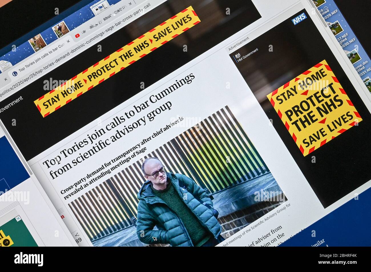 Informations publiques en ligne Coronavirus/ Covid annonce, 'Stay home, Protect the NHS' juxtaposée à un article et une photo présentant Dominic Cummings. Banque D'Images