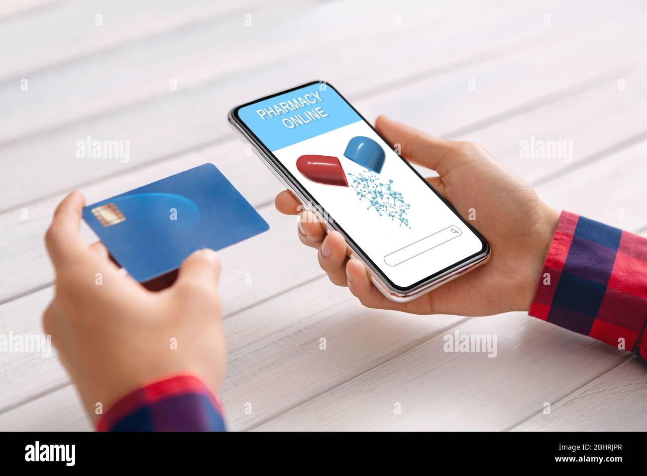 Smartphone avec application de pharmacie en ligne ouverte et carte de crédit en mains mâles Banque D'Images